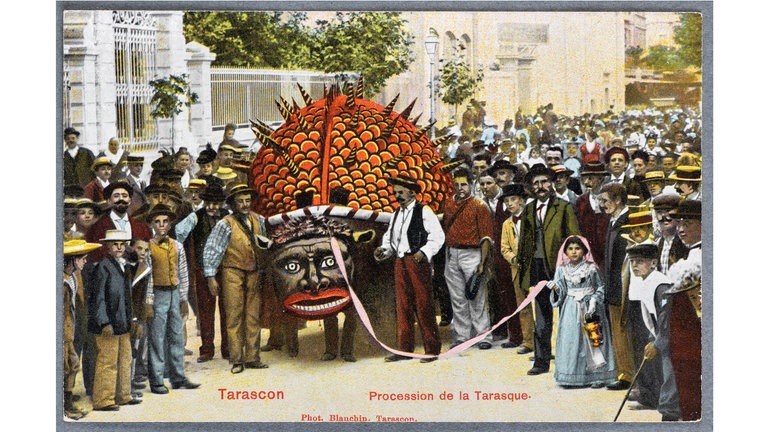 Kolorierte Postkarte mit fotografischer Szene aus dem Festumzug zu Ehren der Zähmung der Tarasque (Drache) durch die Hl. Martha in Tarascon (Frankreich) am 29. Juli 1900