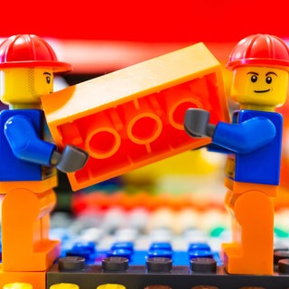 Zwei Lego Bau Arbeiter tragend zusammen einer Orangefarbene Backstein 