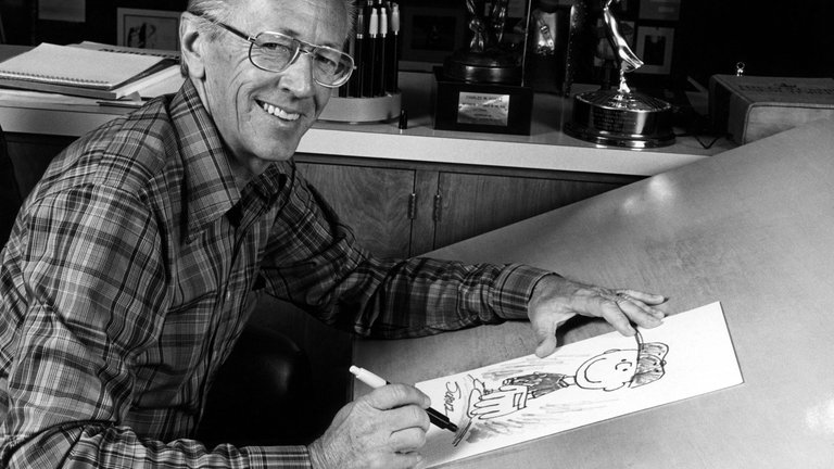 Der Cartoonist Charles M. Schulz in den 70-er Jahren mit einer Comic-Zeichnung