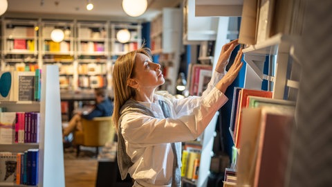 Frau stöbert durch Regale in Buchhandlung 