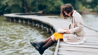 Lesende Frau an einem See, lesenswert Magazin am 24.05.2026