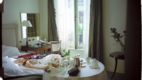 Ein ungemachtes Bett und daneben ein voller Kaffeetisch für zwei Personen.