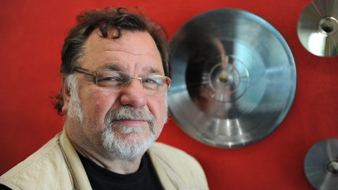 Klaus Lage steht vor einer Schallplatte aus Platin.