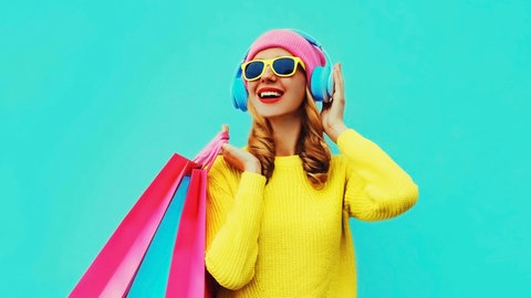Farbenfrohes Porträt einer Frau, die Musik hört und Shopping-Taschen hält