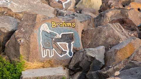 Der Künstler Stoyko Gagamov bemalte die Steine der Wellenbrecheranlage, Santa Cruz, Spanien, mit berühmten Gesichtern aus dem Musikgerne. Im Bild: Johannes Brahms. 