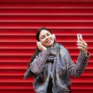 Junge Frau, die mit Kopfhörern tanzt und ein Mobiltelefon in den Händen hält