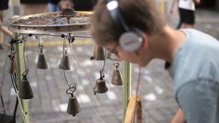Ein Jugendlicher probiert die Klanginstallation "Orkestronia" aus, bei der Eroeffnung des 22. Buskers Festival, am Donnerstag, 7. August 2025, in Bern.