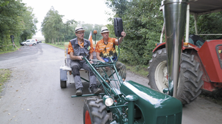 Zwei Männer fahren auf einem Einachser