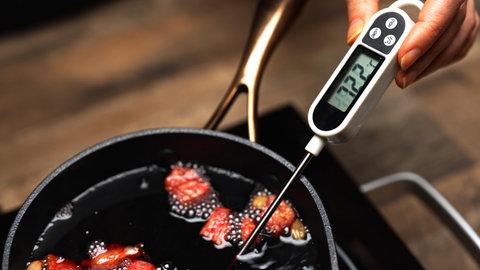 Ein Thermometer wird in einen Topf mit Glühwein gehalten | Weihnachtsmarkt: So erkennt ihr gute Qualität beim Glühwein