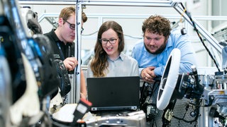 Drei junge Menschen vor einem Laptop in einer Fertigung. Neue Berufe mit Zukunft: Einpacken, eintauchen, die Welt retten. Neue Techniken bringen auch neue Berufe und damit neue Ausbildungen mit sich. Manche sind wenig bekannt, aber ziemlich spannend. Drei Beispiele für Jobs mit Zukunft.