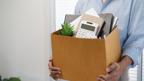 Eine Frau steht mit einem Karton voller Bürosachen in einem Büro | Tipps einer Job-Coachin für den Neustart: So kann ein erfolgreicher Jobwechsel gelingen