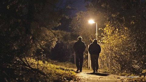 2 Menschen laufen auf dunklem Weg
