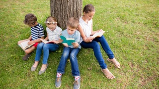Kinder lesen im Park