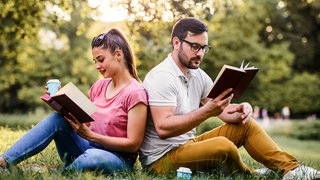 Frau und Mann lesen im Park
