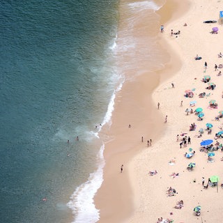 Menschen an einem Strand | Das sind die Reisetrends für euren Urlaub in 2026