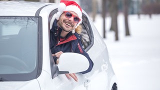 Mann fährt mit Weihnachtsmütze mit dem Auto