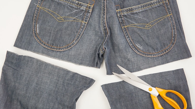Beide Hosenbeine quer und so weit oben wie möglich von der Jeans abschneiden