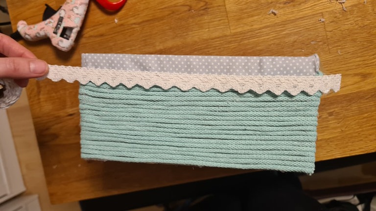 Am oberen Rand der Kordel oder des Stoffes nach Wunsch ein Stück Spitzenband, ein dekoratives Band oder eine extra Kordel als sauberen Abschluss aufkleben. 