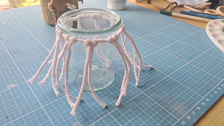 Das Hauptgarn um das Glas schließen und mit einem Knoten befestigen.