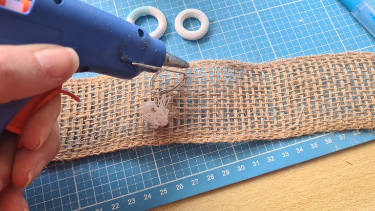 Wenn der Rettungsring fertig ist, wird er mit Garn am breiten Juteband befestigt.
