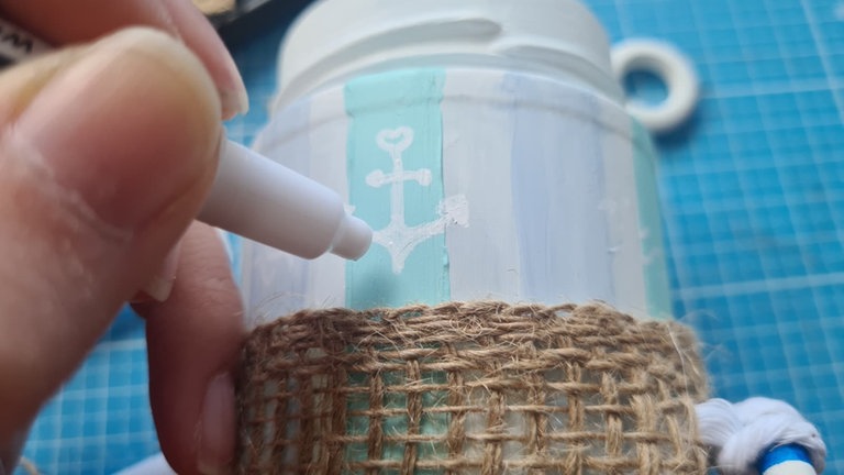 Nun können die Acrylstreifen noch mit weißem Lackstift mit maritimen Symbolen (Anker, Steuerrad, Wellen, Booten oder Fischen) bemalt werden.