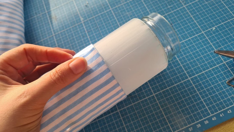 Den Stoff einmal rund um das Glas kleben und die überlappenden Enden verschließen. 