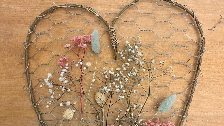 Frische oder getrocknete Blumen werden mit dem Stil durch die Sechsecke im Maschendraht gefädelt. So entsteht ein lebendiges, florales Muster.
