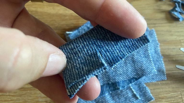Für den Zuschnitt der Blütenblätter die Jeansquadrate mittig falten.