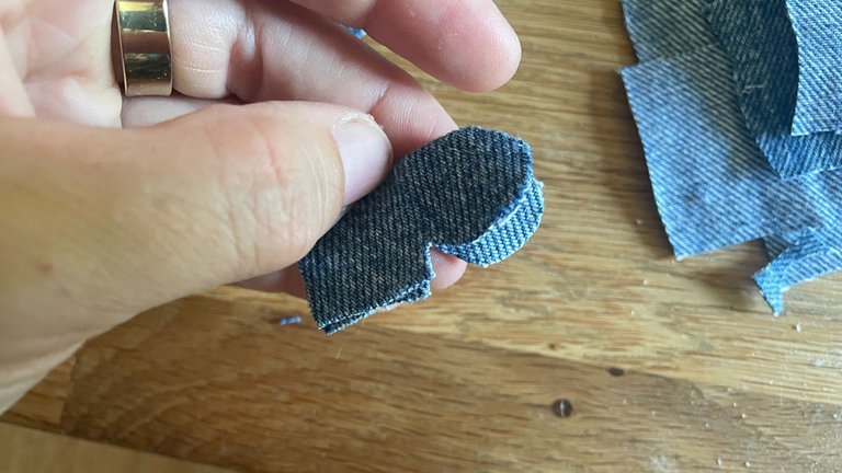 An der offenen Seite (gegenüber der Faltkante) mittig etwa einen Zentimeter tief einschneiden. Von diesem Schnitt aus auf beiden Seiten einen Bogen schneiden.