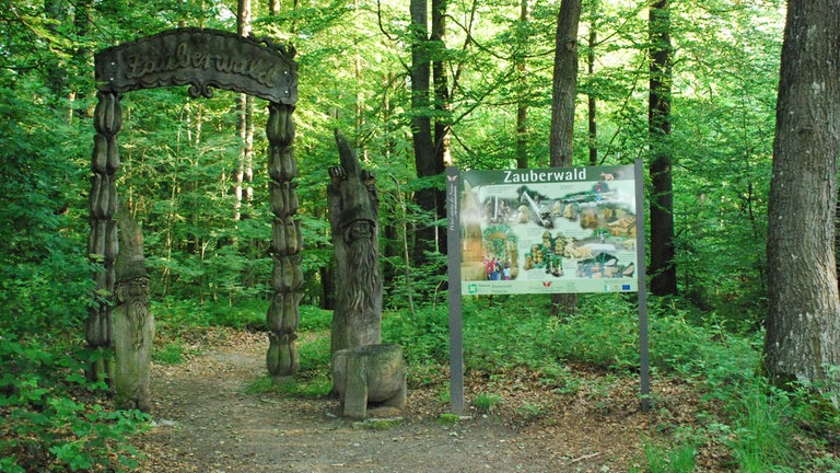 Ein Tor markiert den Eingang zum Zauberwald bei Fichtenau. Hier begegnen Wanderer Zwergen, Hexen und anderen Fabelwesen.