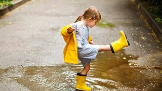 Ein Mädchen spielt in einer Pfütze: Der Mensch braucht, um gesund zu sein, Kontakt mit vielen verschiedenen Mikroorganismen. Das gilt vor allem im frühen Kindesalter.
