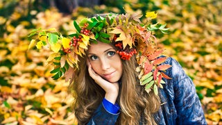 Junge Frau mit Herbstlaub auf dem Kopf: Im Spätsommer und Herbst gehen überdurchschnittlich viele Haarfollikel in eine Ruhephase über und wir verlieren mehr Haare als sonst.