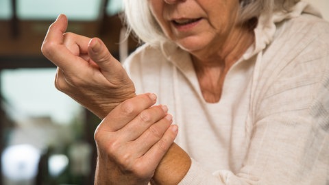 Ältere Frau hält sich das schmerzende Handgelenk: Leider gelingt es an keinem Arthrosegelenk, die Arthrose zu heilen oder die Gelenke in einen Zustand zu bringen, in dem sie in der Jugend waren. Aber es gibt bei der Fingergelenksarthrose und an den Handgelenksarthrosen sowohl konservative als auch operative Maßnahmen, die dem Patienten eine Linderung verschaffen.