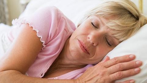Ältere Frau liegt im Bett und schläft