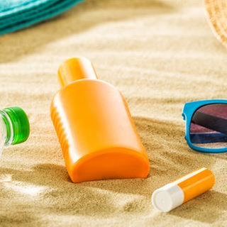 Utensilien für einen Tag am Strand liegen im Sand.