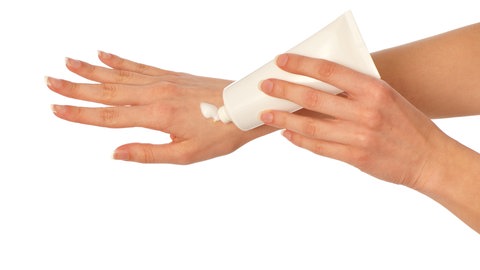 Frau cremt Hand rein - Hautpflege im Winter