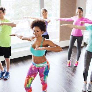 Fünf Personen in bunter Sportkleidung tanzen Zumba
