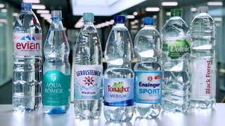 Sieben Flaschen verschiedener Mineralwasser-Hersteller stehen auf einem Tisch. Welches Mineralwasser ist das Beste? Wie gut ist Mineralwasser im Vergleich zu Leitungswasser?