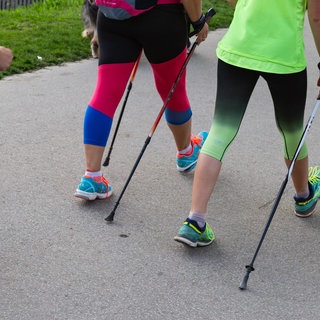 Zwei Personen laufen mit Nordic Walking Stöcken auf einem Weg. Was früher als Training für Biathleten gedacht war, ist heute für viele zum Sport für den Alltag geworden - Nordic Walking. Was ist das genau, und wie effektiv ist dieser Sport?