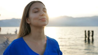 Frau hält ihr Gesicht entspannt in die Sonne