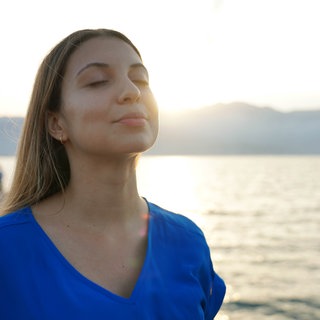 Frau hält ihr Gesicht entspannt in die Sonne