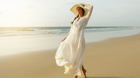 Frau mit einem luftigen Kleid am Strand