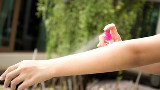 Mückenspray wird auf Arm aufgesprüht