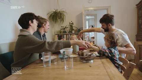 Eine Familie gibt sich vor dem Essen die Hände