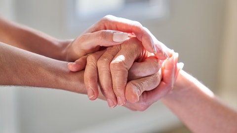 Hände halten von Seniorin als Symbol für Unterstützung und Beistand im Hospiz bei Sterbehilfe | Welthospiztag am 11. Oktober 2025: Ehrenamt im Hospiz: Warum Carlotta Merx Sterbende begleitet