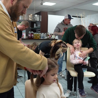 In einem Friseursalon in Bad Kreuznach wird Männern erklärt, wie man mit langen Haaren umgeht und sie frisiert.