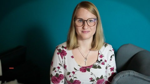Magdalena Hoffmann, eine junge Frau, sitzt auf einem Sessel und schaut in die Kamera.