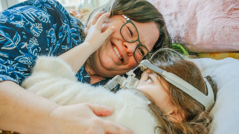 SWR1 Neuanfang: Mama Sabine und Lenya umarmen sich im Bett des Kinderhospiz' Stuttgart.