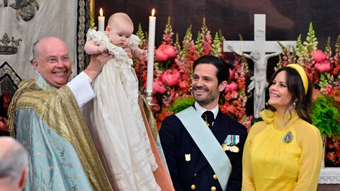 Bischof Johan Dalman hält Prinzessin Ines nach ihrer Taufe hoch, während der schwedische Prinz Carl Philip und Prinzessin Sofia in der Kapelle des Schlosses Drottningholm in Stockholm zusehen.