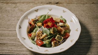 Sommersalat mit Ziegenbratkäse und Croutons auf einem Teller